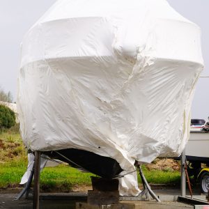 Boat protected by a plastic film for wintering. Sailboat stored for the winter.
